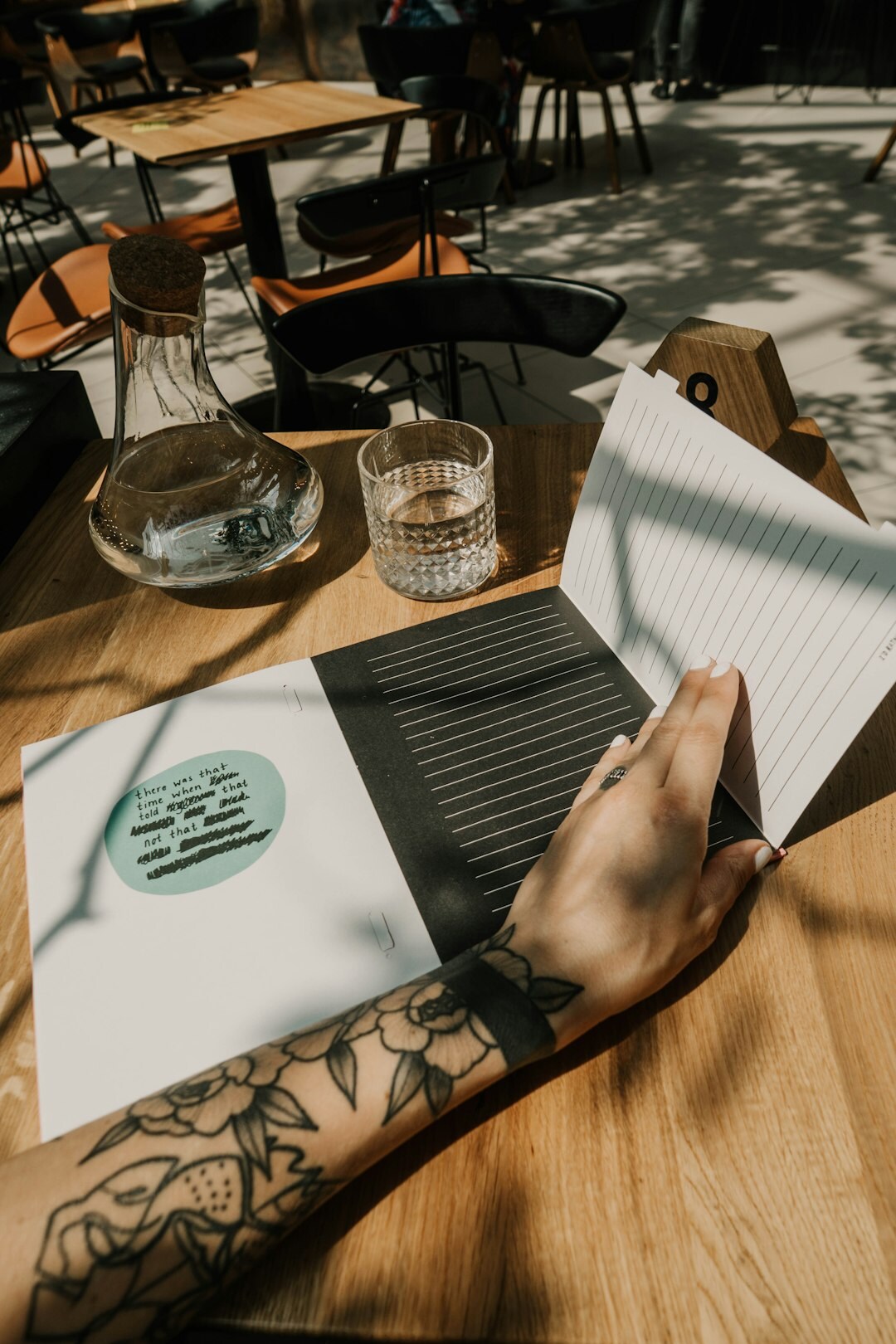 Mãos escrevendo em um caderno de anotações sobre uma mesa